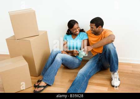 African American maschio e femmina giovane seduto sul pavimento accanto alle caselle di movimento rilassante Foto Stock