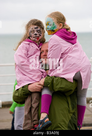 Uomo che porta due bambini Foto Stock