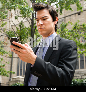 Asian business man standing guardando il telefono cellulare di messaggi Foto Stock