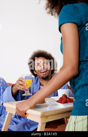 Donna africana portando la colazione a letto al marito Foto Stock