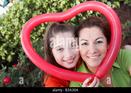 Ispanico madre e figlia tenendo a forma di cuore palloncino Foto Stock