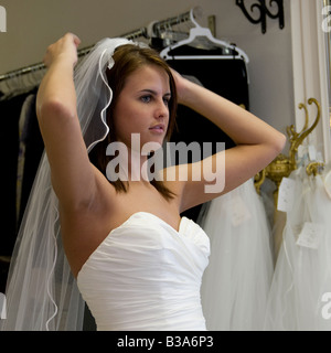 Una giovane sposa cerca su un velo presso il suo abito appena un paio di mesi prima del matrimonio. Stati Uniti d'America. Foto Stock