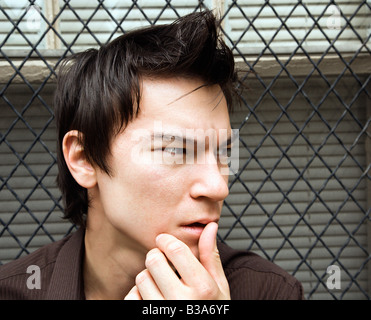 Uomo asiatico accanto alla finestra guardando fuori a lato Foto Stock