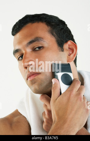 Uomo ispanico faccia per la rasatura con il rasoio elettrico Foto Stock