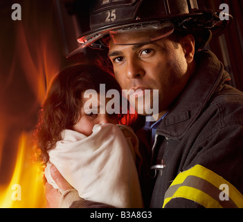 Maschio ispanica pompiere holding bambino Foto Stock