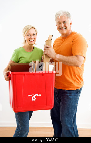 Uomo e donna sorridente mentre si tiene il contenitore di riciclaggio Foto Stock