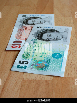 Un £5 e £10 nota ( Sterling ) disposti su una tavola di faggio. Foto Stock