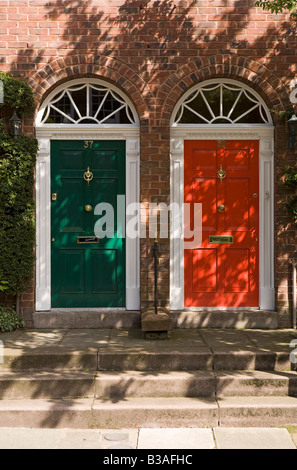 Regno Unito Cheshire Tarporley rosso e verde verniciato porte anteriori di nuova costruzione in stile georgiano case a schiera Foto Stock