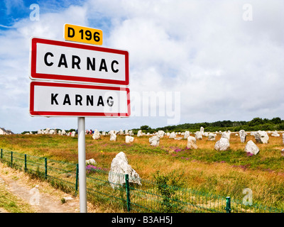 Carnac, Brittany, Francia - Alignements du Menec pietre permanente con il cartello stradale in francese e il bretone lingue Foto Stock