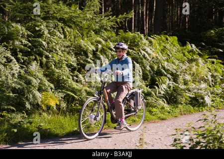 Regno Unito Cheshire Delamere Forest Park donna anziana ciclista sul gigante assistito elettricamente bike Foto Stock