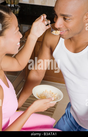 Donna africana alimentazione di cereali al marito Foto Stock