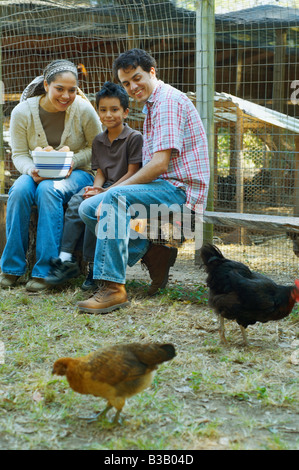 Multi-etnico azienda familiare ciotola di uova accanto ai polli Foto Stock