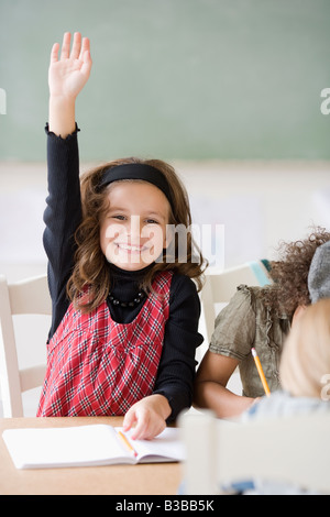 Ragazza alzando la mano in classe Foto Stock