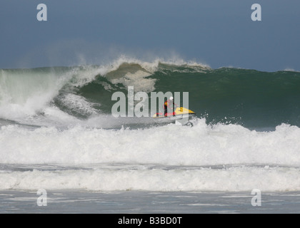 Bagnino RNLI su un jet ski in big surf off Sant Agnese, Cornwall, Regno Unito Foto Stock