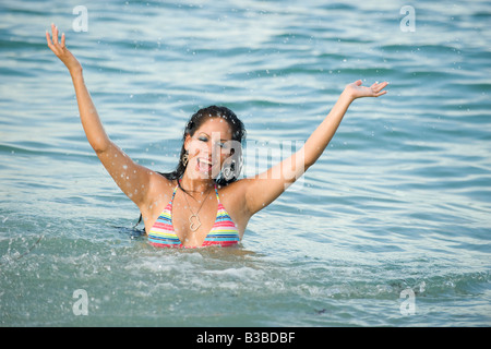 Giovane e bella donna ispanica schizzi nell'oceano Foto Stock
