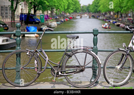 Biciclette olandesi schierate contro un ponte sul canale di Amsterdam Foto Stock