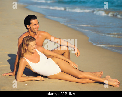Coppia giovane in costume da bagno giacente su una spiaggia Foto Stock