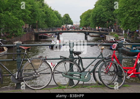 Biciclette olandesi schierate contro un ponte sul canale di Amsterdam Foto Stock