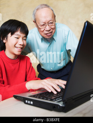 Asian nonno e nipote guardando al laptop Foto Stock