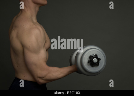 Un uomo di eseguire un bicipite curl con pesi Foto Stock