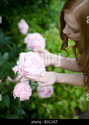 Una donna ammirando i suoi fiori in un giardino Foto Stock