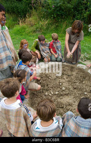 Regno Unito, Galles Pembrokeshire. I bambini sono mostrati come raccogliere fango per costruire graticcio & daub pareti mediante una delle guide al castello di Henllys, ricreato Iron Age Fort costruito sulla sua originali fondamenta vicino a Newport. Foto Stock