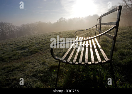 Inghilterra, Shropshire, Ludlow. Ferro battuto panchine su Whitcliffe comune su una nebbiosa mattina di primavera - offrendo incantevoli vedute del castello e della città di Ludlow. Foto Stock