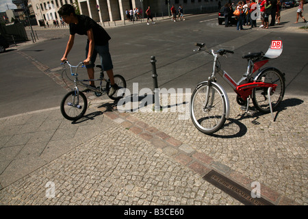 Giovane biker che attraversano la linea simbolica del luogo in cui il Muro di Berlino era stato a Berlino, Germania Foto Stock