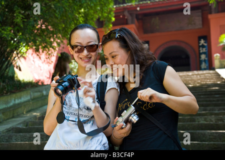 Due giovani donne cinesi guardare foto sulla fotocamera digitale nella parte anteriore di ingresso al Grand Buddha Leshan Dafo Cina Sichuan JMH3228 Foto Stock