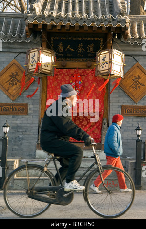 Cina, Pechino, l'Houhai. Un uomo in bicicletta passato un tea shop. Foto Stock