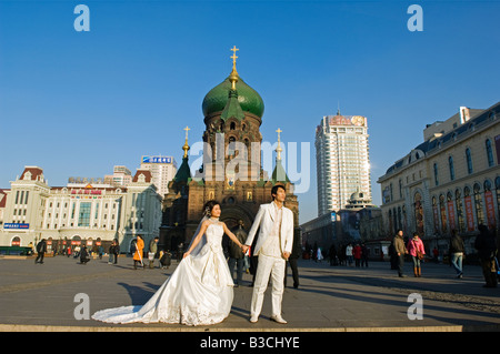 La Cina, a nord-est della Cina, Provincia di Heilongjiang, Harbin città. Un matrimonio giovane posa per foto in pieno inverno nella parte anteriore del Foto Stock