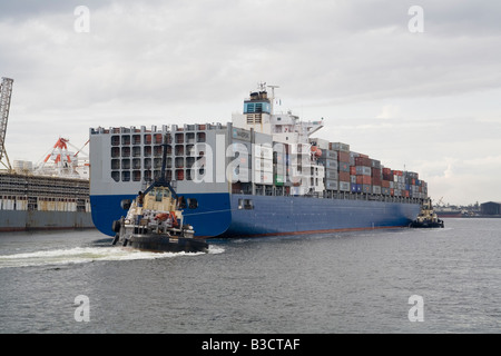 Contenitore nave Maersk Dampier, è guidata nel porto di Fremantle, Western Australia, da due dischi di lavoro barche rimorchiatore Foto Stock