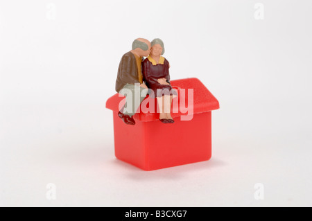 Figurine di plastica seduta sul tetto della casa del giocattolo Foto Stock