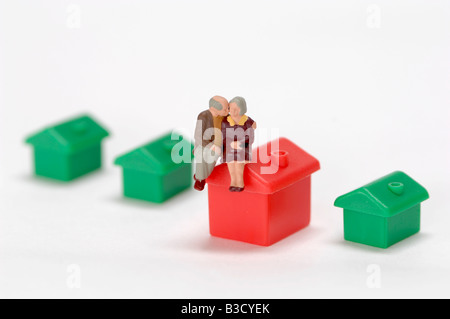 Figurine di plastica seduta sul tetto della casa del giocattolo Foto Stock