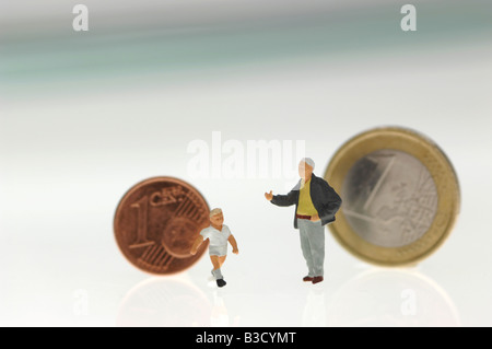 Figurine di plastica e di monete metalliche in euro Foto Stock