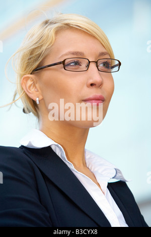 Giovane imprenditrice contemplando fuori ufficio edificio close up Foto Stock