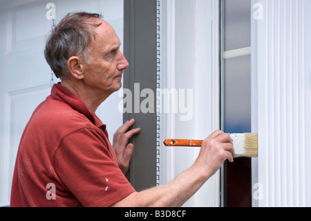 Senior uomo pittura al di fuori di casa Foto Stock