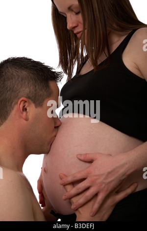 8 mese di gravidanza metà anni venti donna di 25 anni di età con 25 anni partner maschio baciare il baby bump Foto Stock