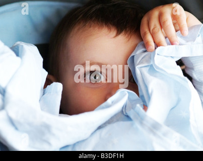 Un bambino si nasconde dietro il suo comfort coperta mentre si siede nel suo passeggino Foto Stock