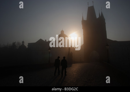 I pedoni a piedi attraverso lo storico Ponte Carlo a Praga con filari di statue barocche polmonato nella nebbia Foto Stock