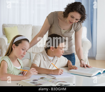 Madre aiutando i bambini con i compiti Foto Stock