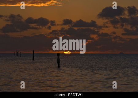 Round orange il sorgere del sole al di fuori del mare in nuvole basse, orange red sky e riflessi arancione in alto nuvole Key Largo, Florida, Stati Uniti d'America Foto Stock