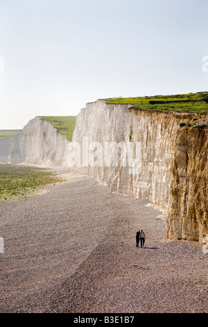 Due escursionisti sulla spiaggia di ciottoli a Birling Gap sul litorale di scogliere bianche in East Sussex England Regno Unito vicino a Beachy Head Foto Stock