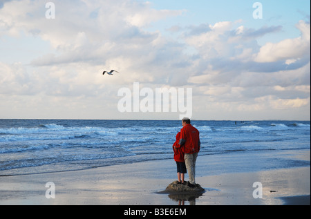 Spiaggia scena con little boy in rosso Foto Stock