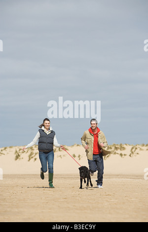 Matura in esecuzione sulla spiaggia con il cane Foto Stock