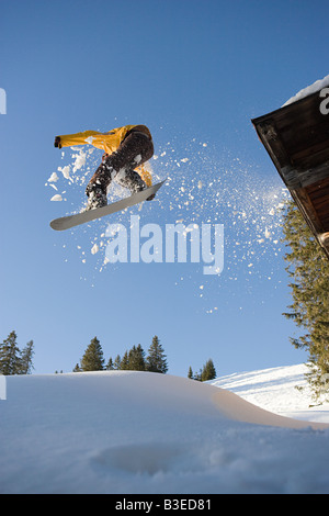 Uno snowboarder salta fuori da un padiglione della cabina Foto Stock