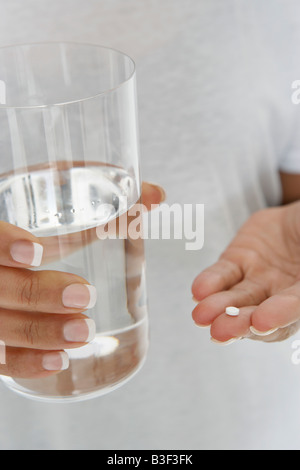 Close-up di donna di mani pillola e bicchiere di acqua Foto Stock