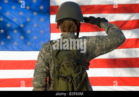 Soldato salutando davanti della bandiera americana Foto Stock