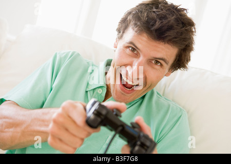 Uomo in sala giocare ai videogiochi sorridente Foto Stock
