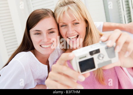 Due donne sul patio utilizzando una fotocamera digitale sorridente Foto Stock